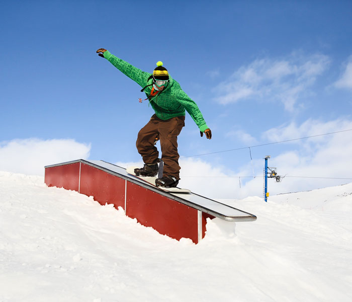 Snowboarder going down a box feature in terrain park